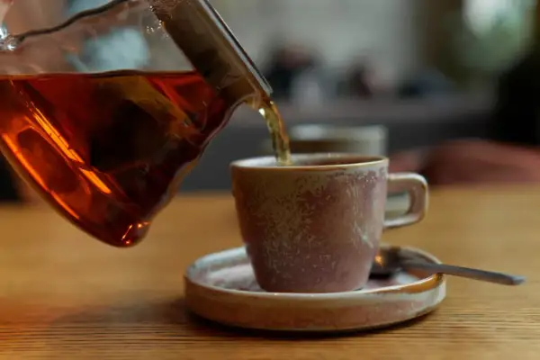 Ciemna czarna herbata nalewana do filiżanki. Osoby z refluksem powinny uważać na ten napój.