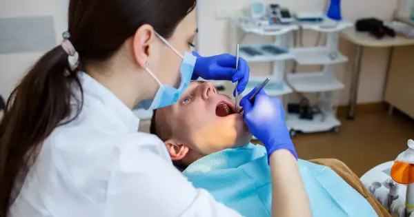 Dentystka bada zęby pacjenta. Czy dentysta może wystawić L4? Tak, jeśli stan zdrowia pacjenta tego wymaga.