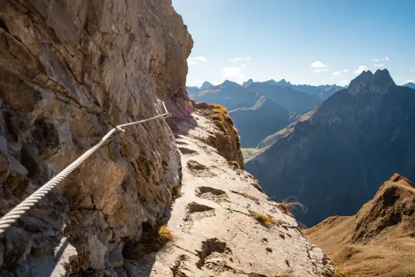 Klettersteig am Laufbacher Eck mit Seilsicherung und Blick auf schroffe Bergketten.