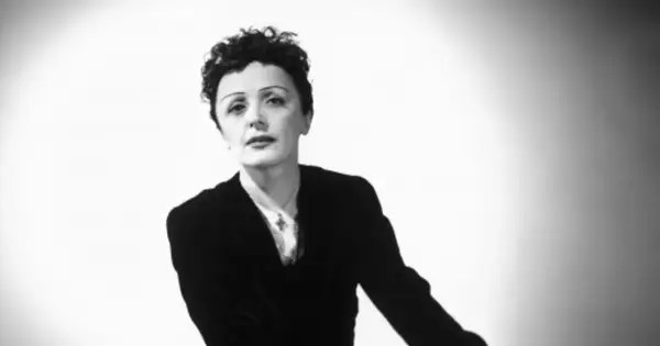Edith Piaf, ikona francuskiej piosenki, w czarnym żakiecie i z charakterystyczną fryzurą. Jej piosenki wciąż poruszają serca.