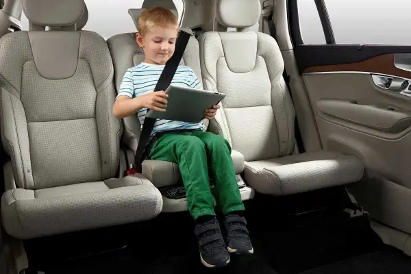 Niño en alzador coche, cumpliendo la normativa de seguridad vial. Viaja entretenido con su tablet.