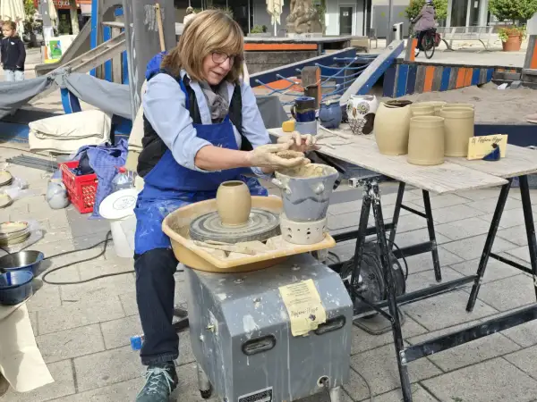 Töpferin am Werk am Hafenmarkt Heilbronn. Sie formt mit geübten Händen Ton auf ihrer Töpferscheibe.
