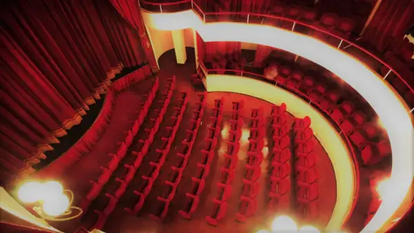 Interno del teatro cometa off, con file di poltrone rosse vuote e tende di velluto.