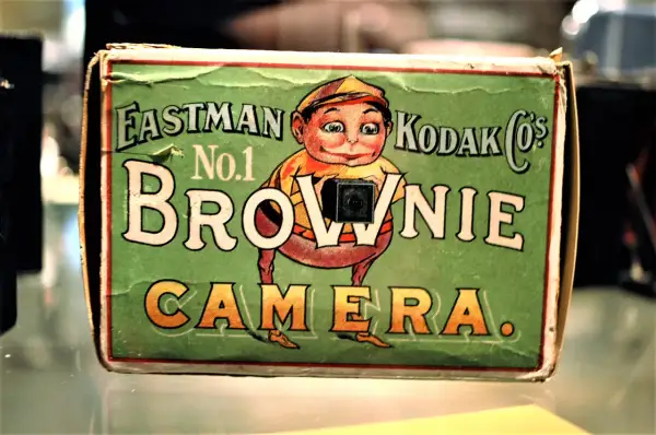 En grön låda med en tecknad figur som håller en kamera. Texten "Eastman Kodak Co.'s No.1 Brownie Camera" syns tydligt.