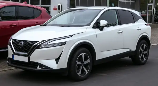 Un Nissan Qashqai blanc, parfait pour la ville, avec des jantes modernes. Ses dimensions sont idéales pour le stationnement.