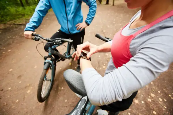 Para sprawdzić, ile kalorii spaliła na rowerze, kobieta sprawdza swój smartwatch po przejechaniu 5 km.