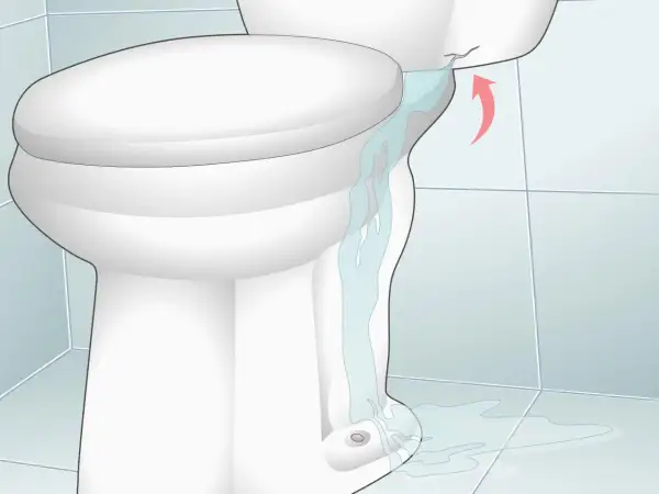 Water is leaking from a cracked toilet tank, causing low water in the toilet bowl and a puddle on the floor.