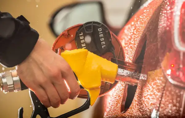 Mano che inserisce la pompa gialla nel serbatoio con la scritta "DIESEL". Attenzione a non confondere la benzina nel diesel!