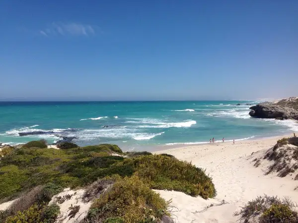 Türkisblaues Meer und Sanddünen im De Hoop Nature Reserve. Kleine Figuren genießen den Strand.