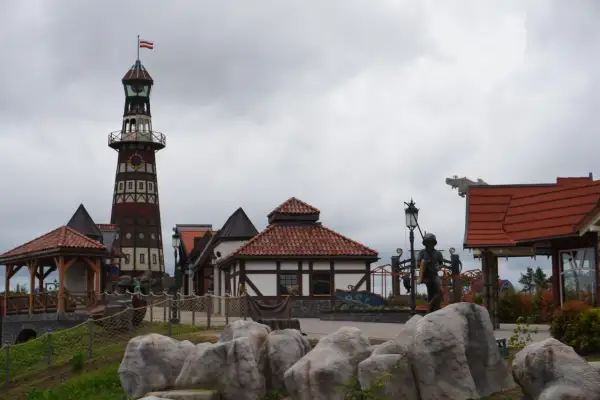 Wesołe miasteczko Hossoland kiedy otwarcie? Widok na latarnię morską, domki w stylu portowym i rzeźby.