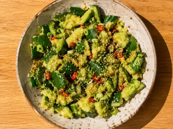 En skål med krossad gurksallad, toppad med sesamfrön, chili och salladslök. Ett perfekt gurksallad recept för sommaren.