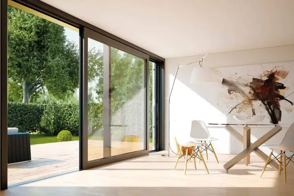 Amplias ventanas correderas modernas conectan un comedor minimalista con un jardín exuberante, mostrando diferentes tipos de ventanas modernas.