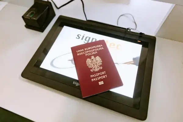 Polski paszport leży na ekranie urządzenia do podpisu elektronicznego, obok skanera linii papilarnych. Ważność paszportu jest kluczowa przy podróżach.