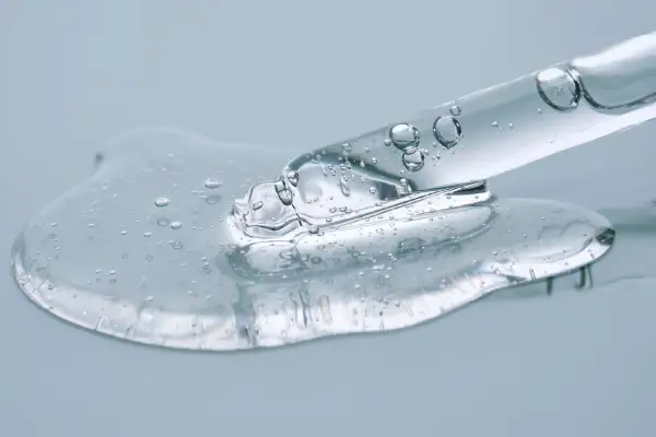 Kropla przejrzystego serum z bąbelkami powietrza spływa z pipety. To połączenie ceramidów a peptydów dla zdrowej skóry.