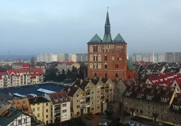 Widok na ceglaną wieżę kościoła i zabudowania miejskie Kołobrzegu.