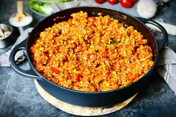 Herzhafter Djuvec Reis mit Mais und Paprika in einer Gusseisenpfanne, bereit zum Servieren.