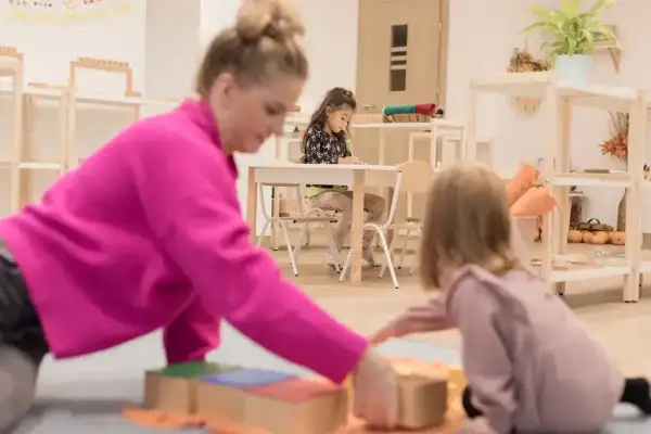 Nauczycielka pokazuje dzieciom, co to montessori, podczas zabawy klockami.