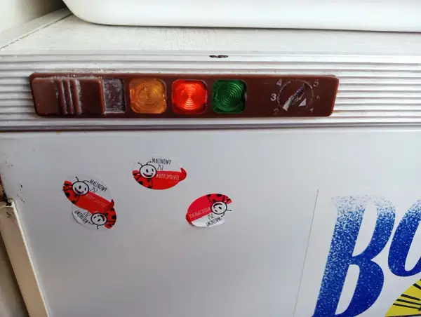 Stara lodówka Polar z kontrolkami i pokrętłem termostatu. Na drzwiach naklejki z biedronkami i napisem "Malinowy".