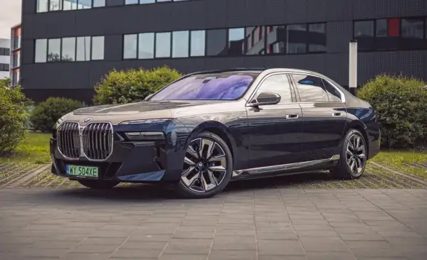 Eleganckie BMW i7 w ciemnym kolorze prezentuje się luksusowo przed nowoczesnym budynkiem.