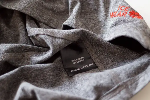 Szara koszulka z metką: 92% poliester, 8% spandex. Poliester co to za materiał? Wytrzymały i szybkoschnący, idealny do odzieży sportowej.