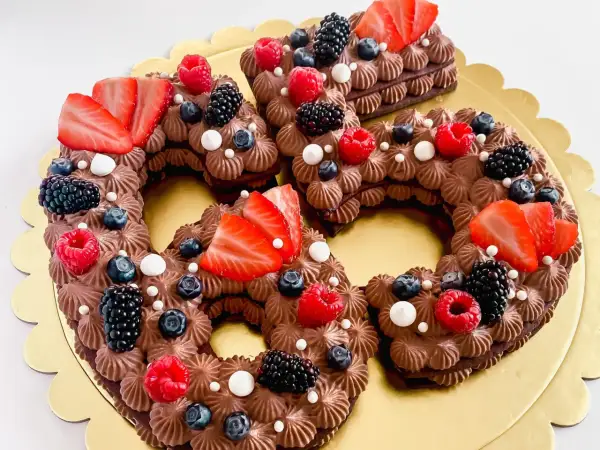 Una torta numero cioccolato, decorata con fragole, lamponi, mirtilli e more.