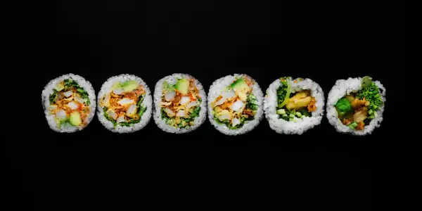 Sześć kawałków futomaki, czyli dużych rolek sushi, z awokado, warzywami i smażonymi kawałkami.