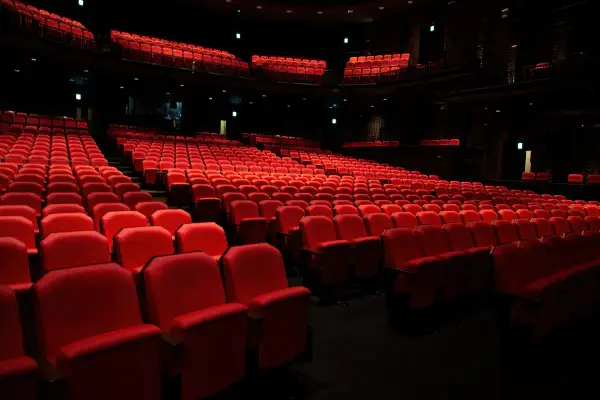 Puste czerwone fotele w teatrze, czekające na widzów. Zastanawiasz się, ile trwa spektakl w teatrze?