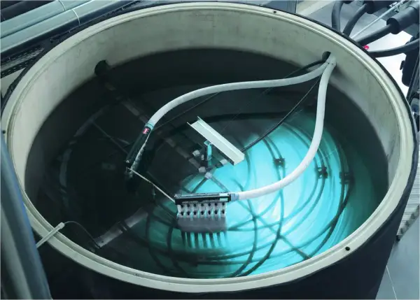 Ein großer Tank mit Wasser, Rohren und einem Gerät zur Eisbildung. Hier wird ein **Eisspeicher selber bauen**-Projekt umgesetzt.