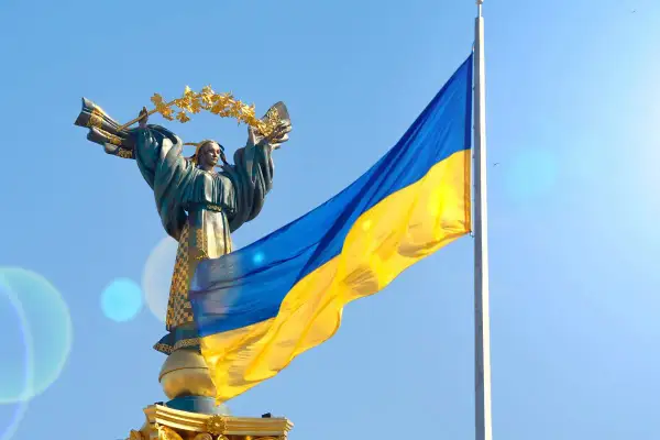 Pomnik z wieńcem laurowym i flaga Ukrainy na tle błękitnego nieba. Duma i nadzieja na wolność na Ukrainie.