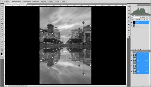 Interface Photoshop : une image de ville en noir et blanc avec ses reflets dans l'eau. Le calque "Layer 1" est sélectionné, prêt à mettre un calque en noir et blanc.