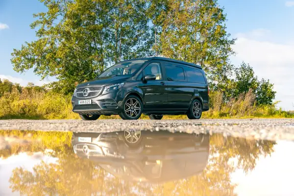Mörkgrå Mercedes-Benz Vito med takhöjning, perfekt för service och äventyr. Reflekteras i en vattenpöl.