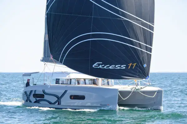 Catamarano Excess 11 con vela nera che naviga in mare aperto.