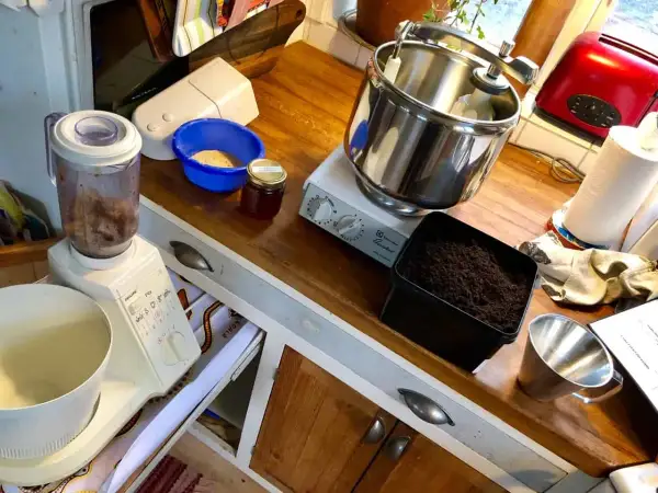 Förbereder för att mala tobak till snus. Köksbänk med mixer, skål med tobak, burk med honung och en köksmaskin.