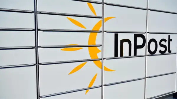 Zbliżenie na białą paczkomat InPost z żółtym logo i czarnym napisem.