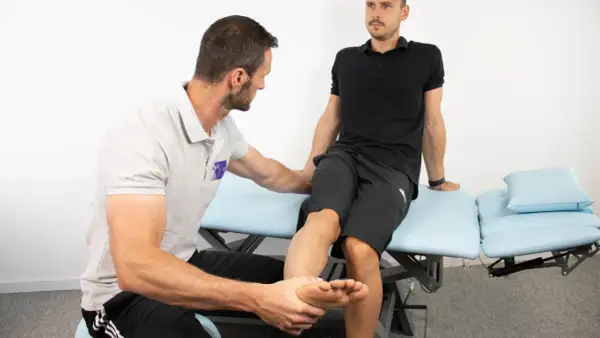 Fysioterapeut utför piriformis syndrom test på patient som sitter på en undersökningsbrits.