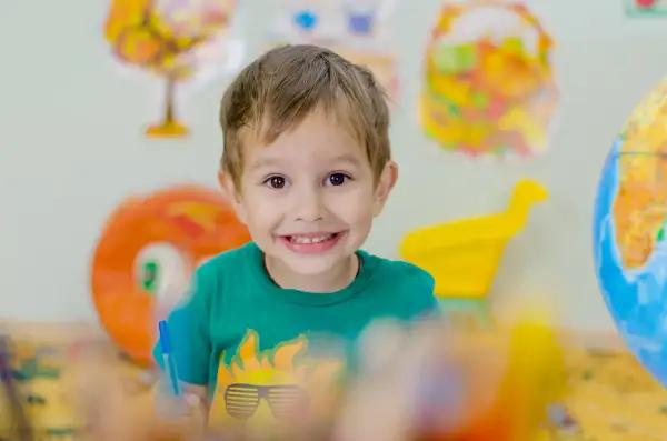 Niño sonriente con camiseta verde, aprendiendo sobre el mundo. Fomenta la autoestima en niños de 6 a 12 años.