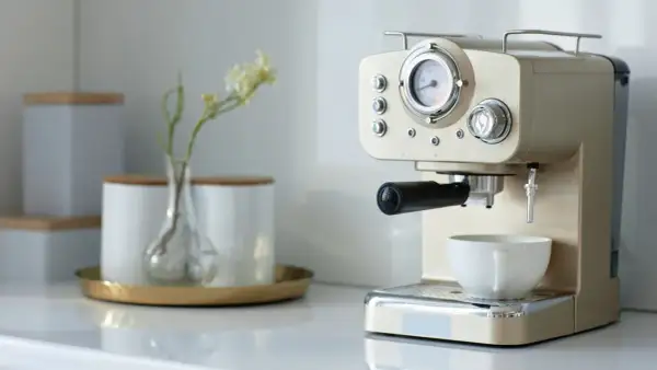 Kaffee-Ecke-Ideen: Eine elegante Espressomaschine mit Tasse und einer kleinen Vase mit Blumen.