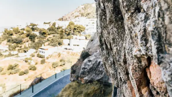 Roca en primer plano con vistas a un pueblo blanco en la sierra de Gador.