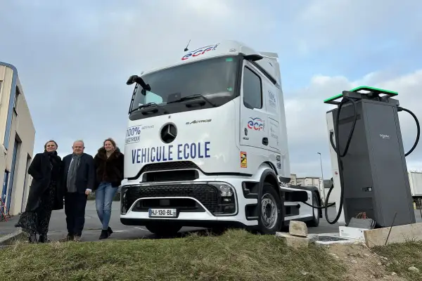 Trois personnes posent devant un camion école 100% électrique, prêt à être rechargé. L'avenir des camions électriques est en marche.