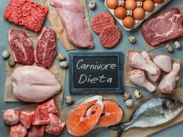 Różnorodne mięsa i ryby, jajka, kości. Tabliczka z napisem "Carnivore Dieta" sugeruje, że to składniki diety mięsożercy.