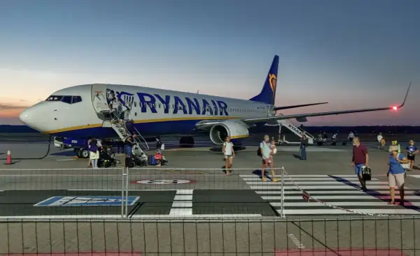 Ryanair przyloty Modlin: pasażerowie schodzą po schodkach z samolotu na płycie lotniska o zmierzchu.