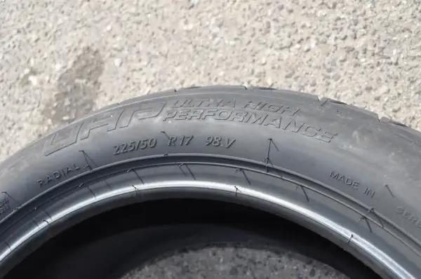 Opona samochodowa z napisem "ULTRA HIGH PERFORMANCE", rozmiar 225/50 R17 98V. Wygląda jak kormoran nurkujący w wodę.