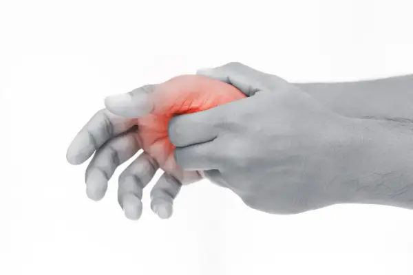Schmerzende Hand, die den Daumen mit roter Markierung hält, was auf Schmerzen im Daumengelenk hinweist.