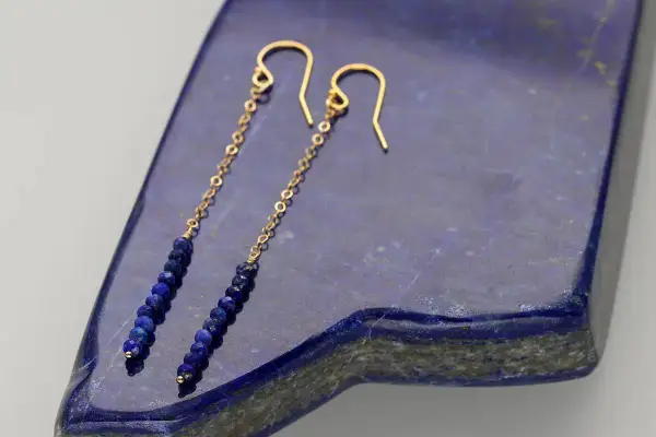 Eleganckie kolczyki z lapis lazuli na złotym łańcuszku, zakończone zapięciem bigiel.