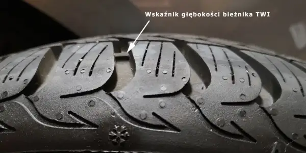 Zbliżenie na bieżnik opony z widocznym wskaźnikiem głębokości TWI.