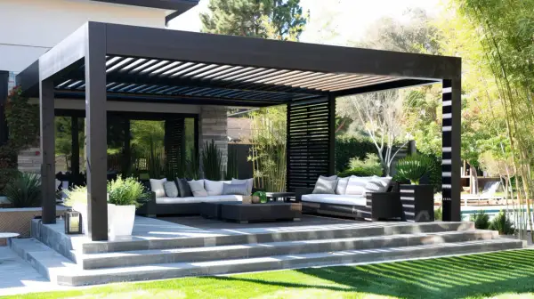 Nowoczesna, czarna pergola przed wejściem do domu, z wygodnymi sofami i stolikami, tworzy idealne miejsce do relaksu na świeżym powietrzu.