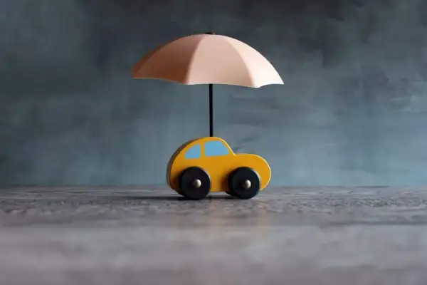 Voiture jaune sous parapluie, symbolisant une assurance courte durée.