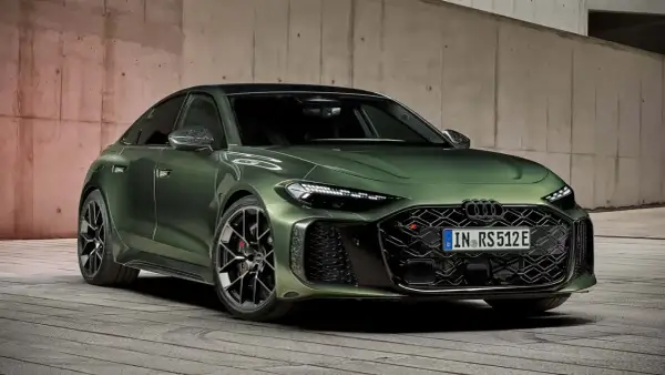 Elegancki, zielony Audi A5 Coupe z agresywnym grillem i sportowymi felgami, zaparkowany na drewnianej podłodze przy betonowej ścianie.