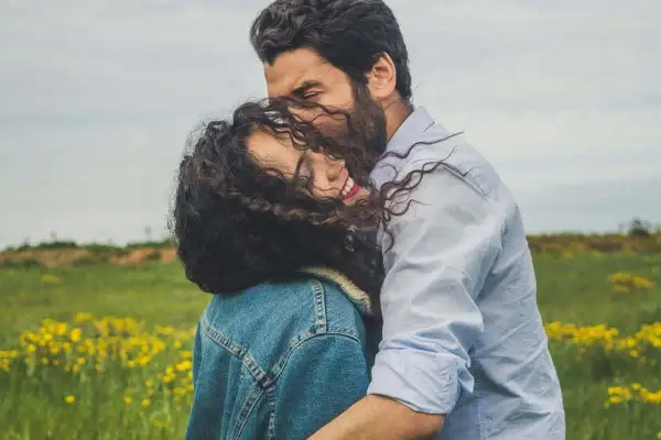 Un abbraccio intenso in un prato fiorito, un momento di pura comunicazione di coppia, dove sguardi e gesti parlano più delle parole.