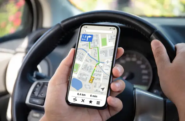 Ręce kierowcy trzymają telefon z nawigacją, co jest niebezpiecznym korzystaniem z telefonu podczas jazdy rowerem.